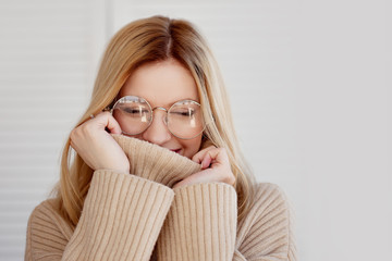 Young beautiful woman in beige sweater and glasses. Attractive blonde