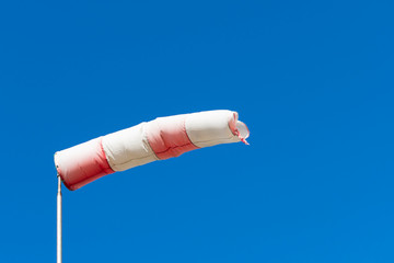 Red White windsock indicating from where the wind comes with a blue background