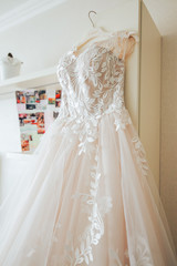 Fototapeta na wymiar beautiful wedding dress hanging on a hanger in the room of the bride