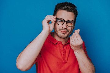 Fototapeta premium Half length of handsome guy in glasses squinting on blue background