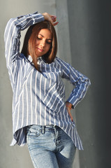 Young beautiful asian girl stands near the wall and posing and she dressed a striped shirt