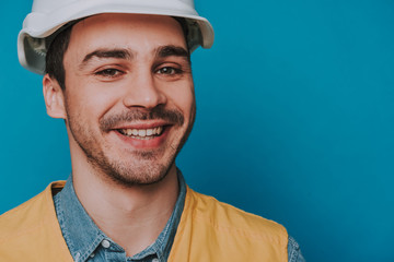 Cropped photo of happy guy wearing helmet and vest on blue background