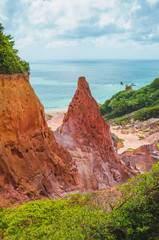 Rock formations called Pico Castelo da Princesa - princess castle at Praia de Coqueirinho, Costa do Conde PB, Brazil. Rocks with red and orange tones with a central pointed rock, sea on background.