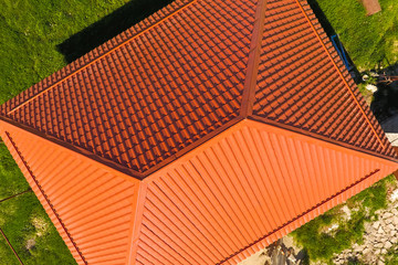 House with an orange roof made of metal, top view. Metallic profile painted corrugated on the roof.