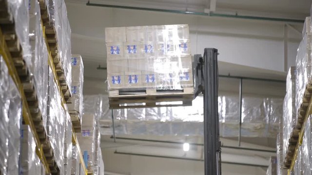 Warehouse worker driver loading cardboard boxes by forklift stacker loader furnirure storage boards