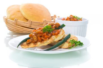 fried bread toasts with stewed beans and vegetables in a plate