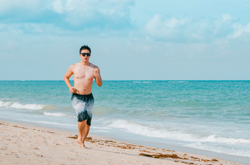 Man running on the beach during summer. Doing cardio exercise on the sand. Photo at Praia de Tabatinga 2, Conde PB Brazil. 