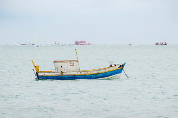 Naklejka na ściany i meble Small boat anchored in the middle of the sea. Small rusty fishing boat.