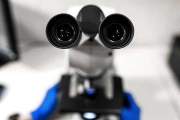 Closeup point of view of laboratory assistant looking through microscope lens