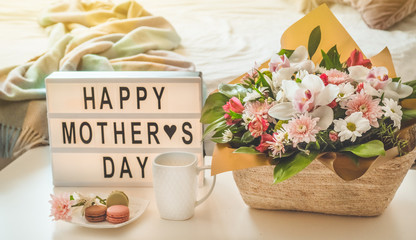 Happy mothers day. A beautiful bouquet of flowers with hot tea on the table. Breakfast in bed on Mothers day. 