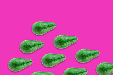 Diagonal rows of green whole fresh raw avocados on pink background with copy space for your text