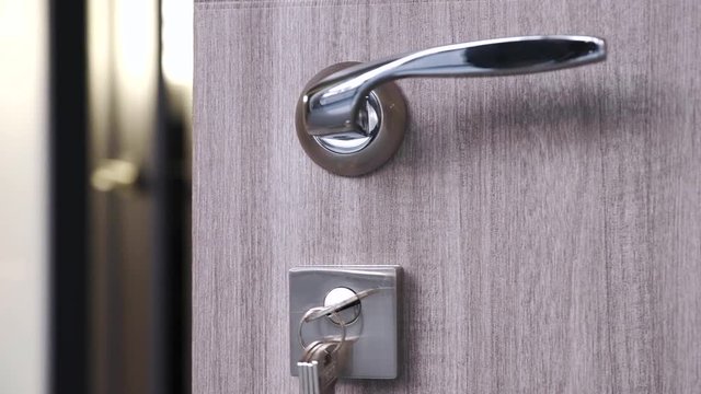 Entrance doors of light tone wood structure of a tree with a door handle and keys in the lock.