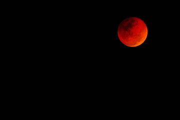 Big red moon with negative space for text, black background.