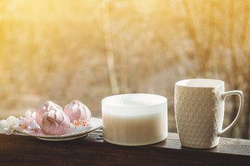 Cozy spring still life: cup of hot tea with spring bouquet of flowers on vintage windowsill with a pink marshmallow. Spring. Apartment.