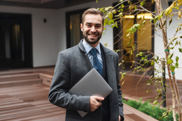 Attractive young businessman wearing suit walking