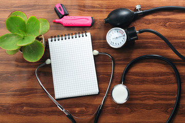 medical concept text writing on white notebook and black stethoscope,  sphygmomanometer on wood...