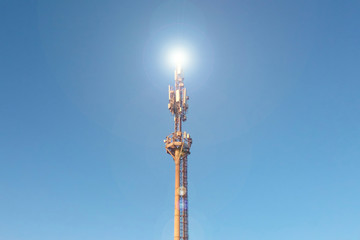 TV tower broadcasting, metal tower against the blue sky, the bright light of the signal to broadcast