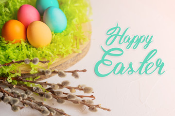 Easter eggs on the grass with willow branches with the text Happy Easter