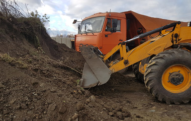 Wheel loader excavator with backhoe unloading sand at eathmoving works in construction site quarry
