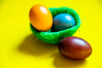 Easter eggs in a green basket on a yellow background.