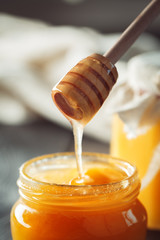 Honey background. Sweet honey in glass jar on wooden background.