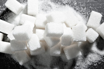 Sugar lumps piled up together against a black background