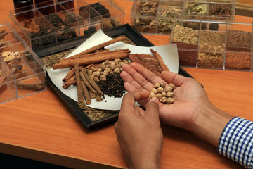 Doctor holding dry herbal on a wooden background with all dry herbs ingredients. Herbal teas beverage for chinese or thai traditional alternative medicine therapy. 