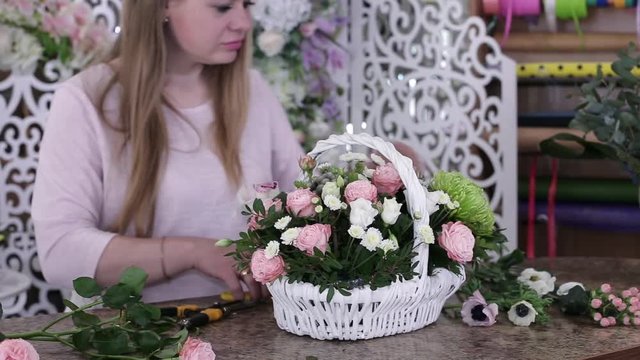 Woman Florist Making Beautiful Flower Bouquet of roses in white basket.