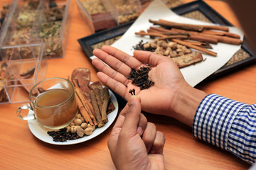 Hand holding dry herbal on a wooden background with all dry herbs ingredients. Herbal teas beverage for chinese or thai traditional alternative medicine therapy. 