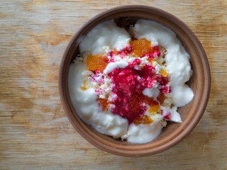 Top view on a bowl with cottage cheese, yogurt, raspberry mash and honey