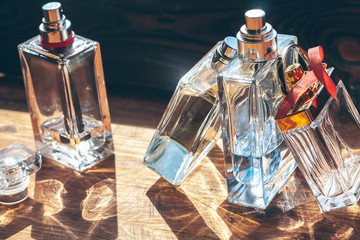 Several bottles with perfume in rays of sunshine on wooden table