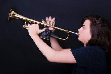 Portrait of a teenager playing trumpet in studio.