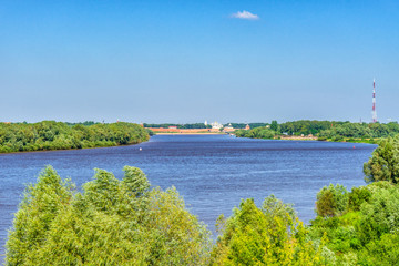 Fototapeta na wymiar Picturesque summer landscape with view from hill to Volkhov river and ancient Kremlin on horizon. Beautiful scenery with architectural landmark. Velikiy Novgorod, Russia