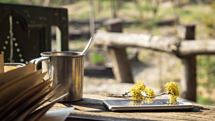 Metal mug, a flowering branch and a telephone on a wooden table