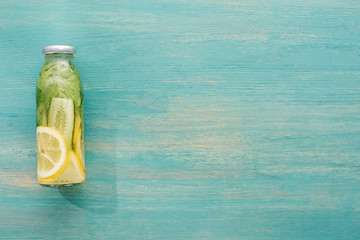 Obraz premium top view of detox drink in bottle with fresh lemon and cucumber slices and green mint