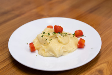 Close up of mash potato with slice potato on wooden table.