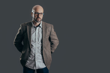 Serious middle aged man with a deadpan face expression dressed in casual posing on a dark gray background