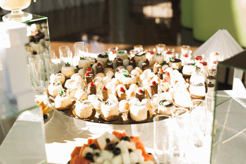 Delicious and tasty dessert table with cupcakes shots at reception closeup