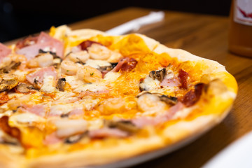 Closed up of seafood pizza on wooden table.