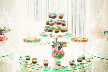 Delicious sweets on wedding candy buffet with desserts, cupcakes