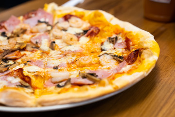 Closed up of seafood pizza on wooden table.