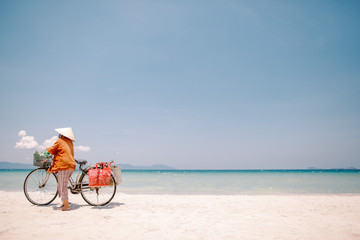 Fototapeta na wymiar Beach seller in a hat with a bicycle