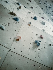 Grey wall with colourful climbing holds for rock climbing activity.