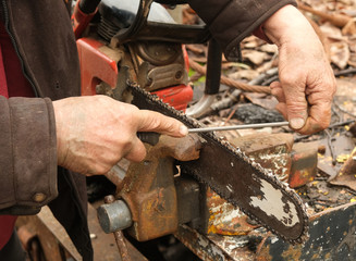 Working man's hands filing a saw blade