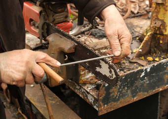 Working man's hands filing a chain saw blade 2