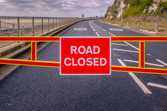 Red Road Closed Barrier Across An Empty  Tarmac Road With White Road Markings And 30 Mile Per Hour Sign.