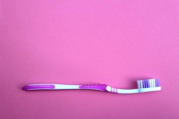 One toothbrush lies on a pink background