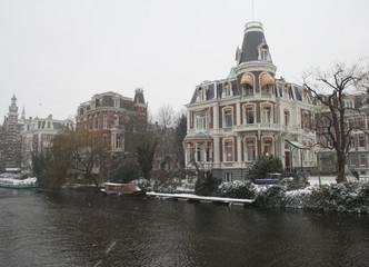 Naklejka premium Snowy landscape in Amsterdam with boats and houses
