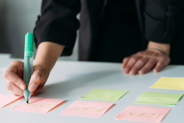 Business strategy design. Corporate brainstorming and brainwork. Woman using sticky labels to take notes.