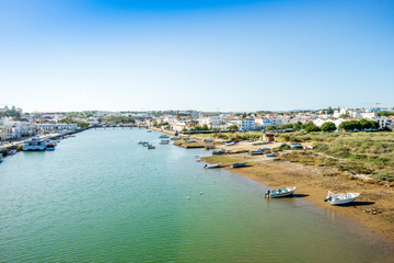 Fototapeta premium Cityscape fo Tavira with fisherman boats and roman bridge over Gilao river, Portugal
